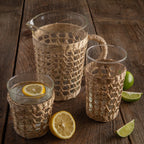 Be Home Seagrass rattan wide cage tumbler in hand-woven rattan over glass, styled in a room setting (2)