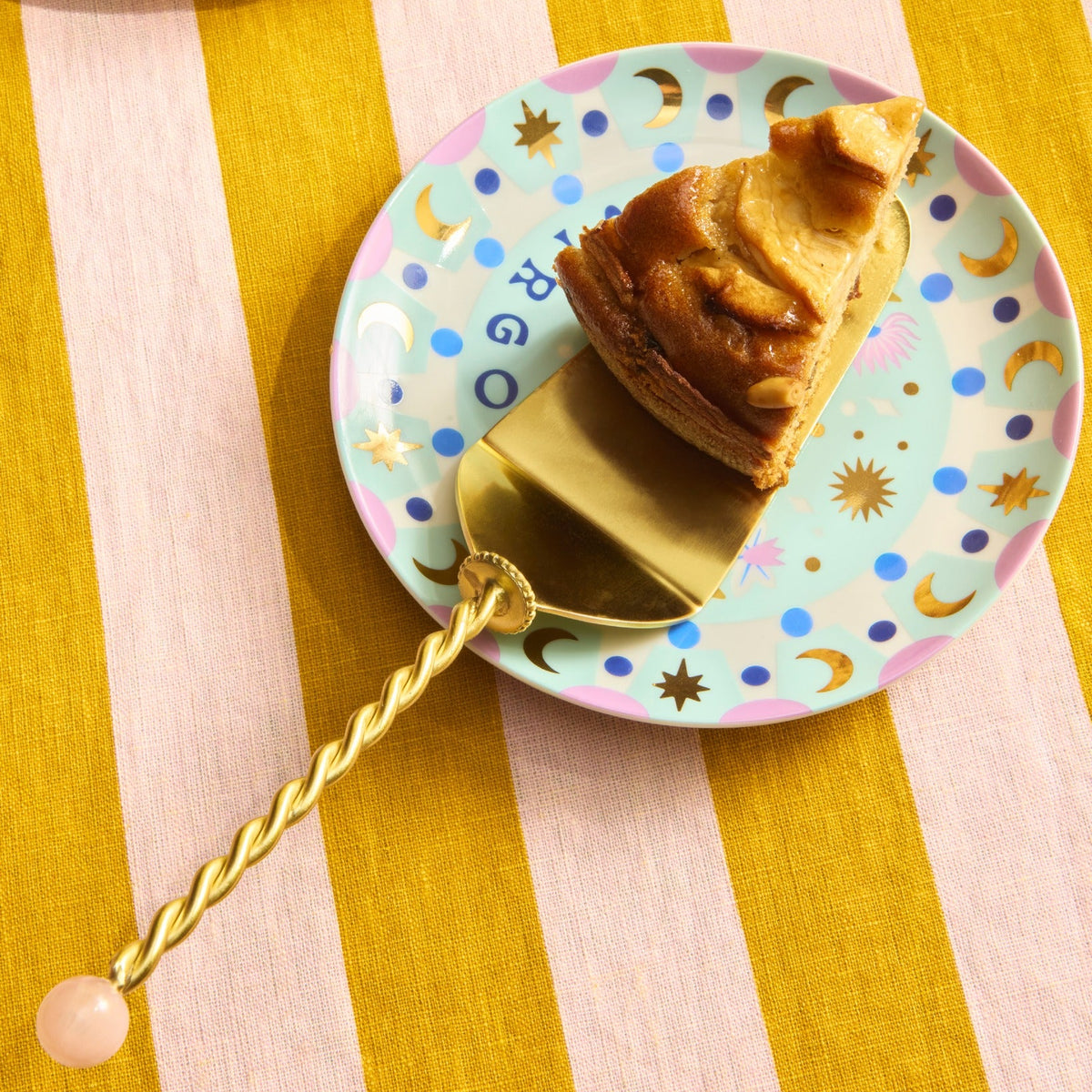 Bitossi Home Torchon gold cake server with twisted handle, 27.5cm, styled in a table setting